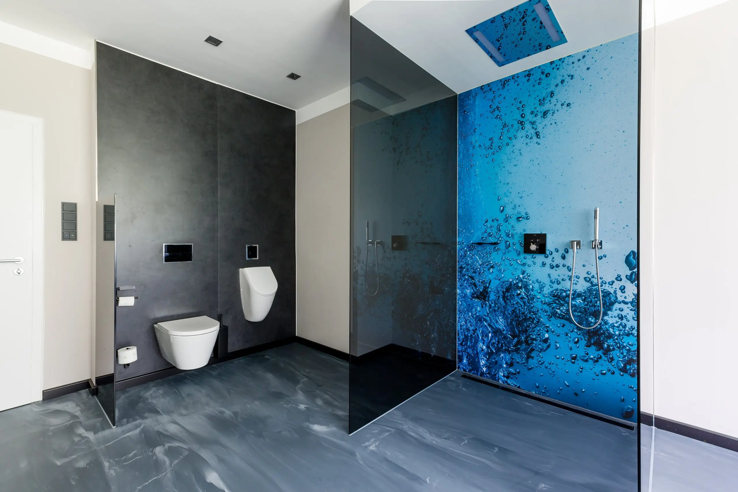 Sanitärbereich mit dunklem Steinboden und blau gemusterter Glaswand