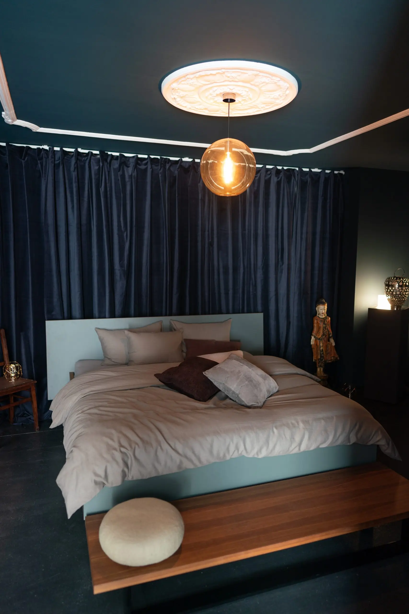 Schlafzimmer mit dunkelblauer Wand, Holzbett und warmer Pendelleuchte