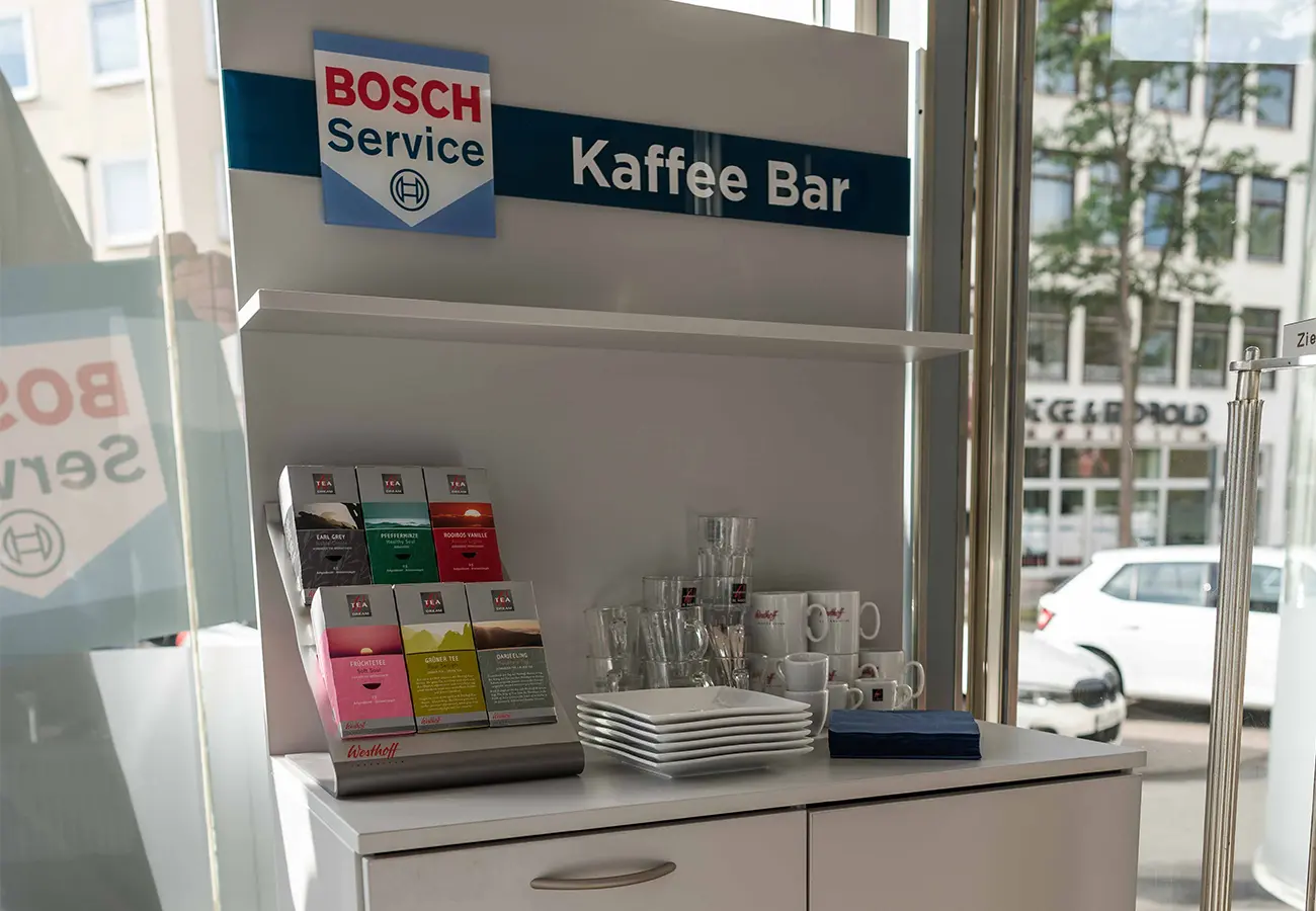 Kaffeebar mit Teesortiment und Tassen unter dem Schild Kaffee Bar