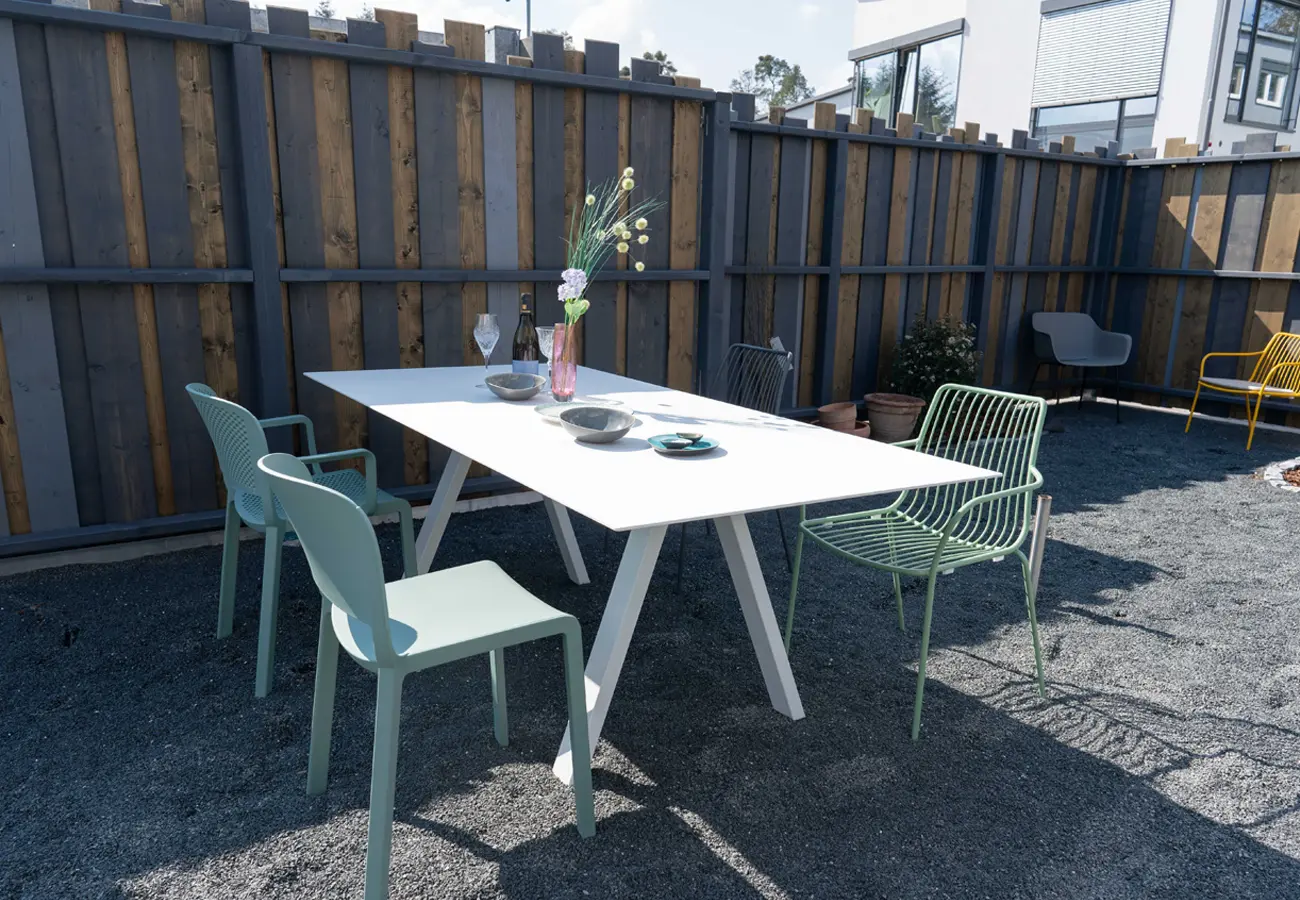 Weißer Gartentisch mit grünen Stühlen