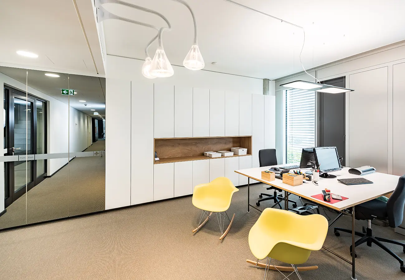 Arbeitsplätze mit weißer Schrankwand und gelben Schalenstühlen