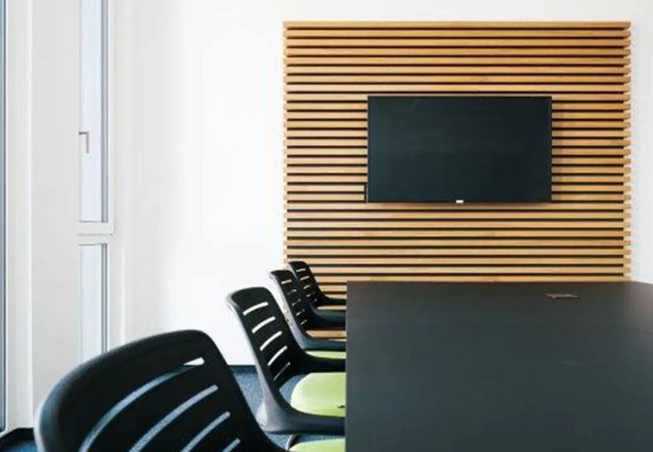 Besprechungsraum mit Bildschirm an der Holzlamellenwand