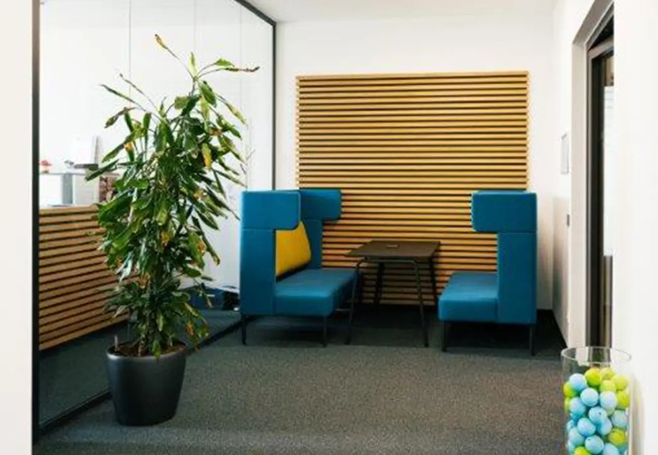 Besprechungsecke mit blauen Sesseln vor einer Holzlamellenwand