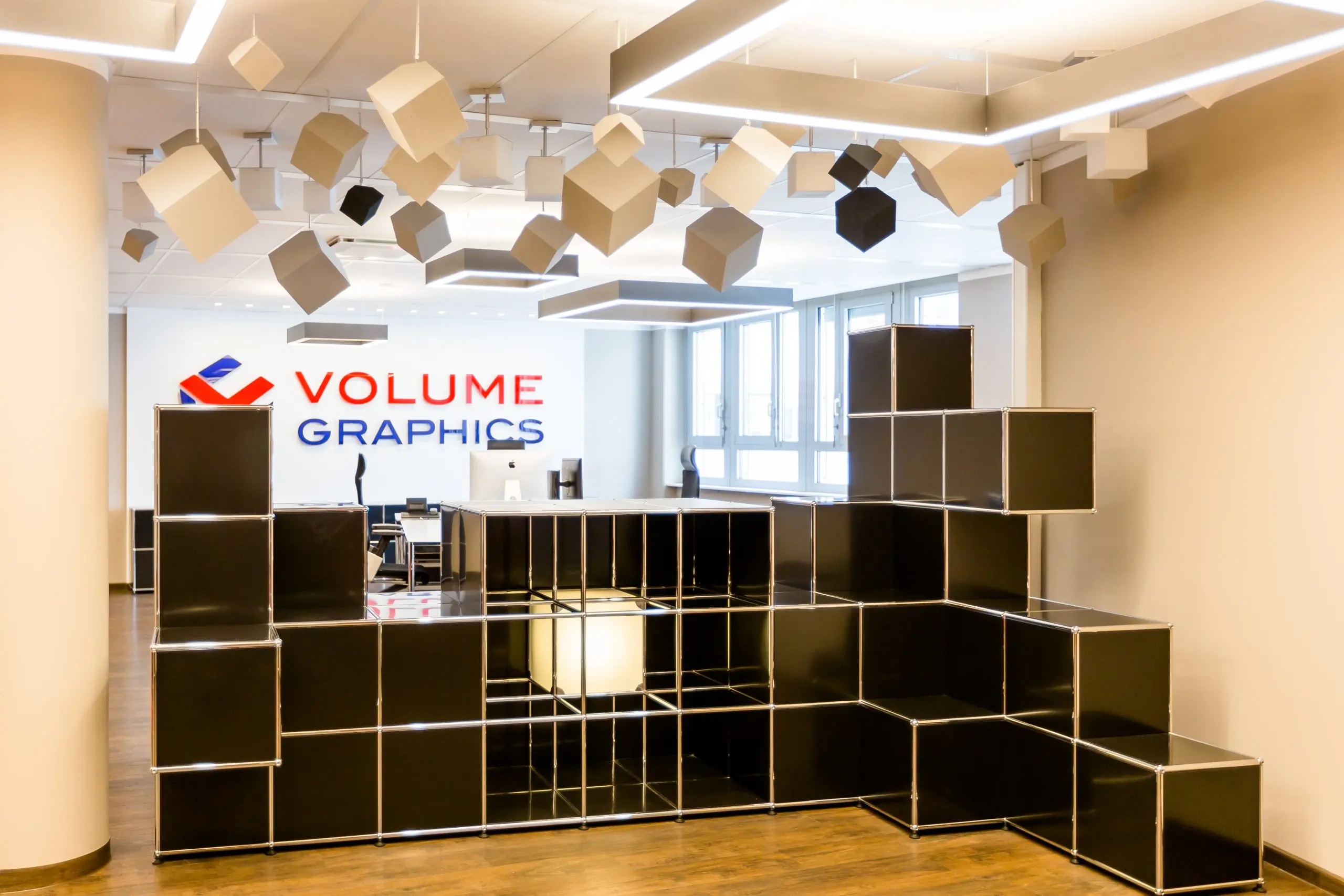 Empfangsbereich mit gestuftem USM-Haller-Möbel und Firmenlogo an der Wand