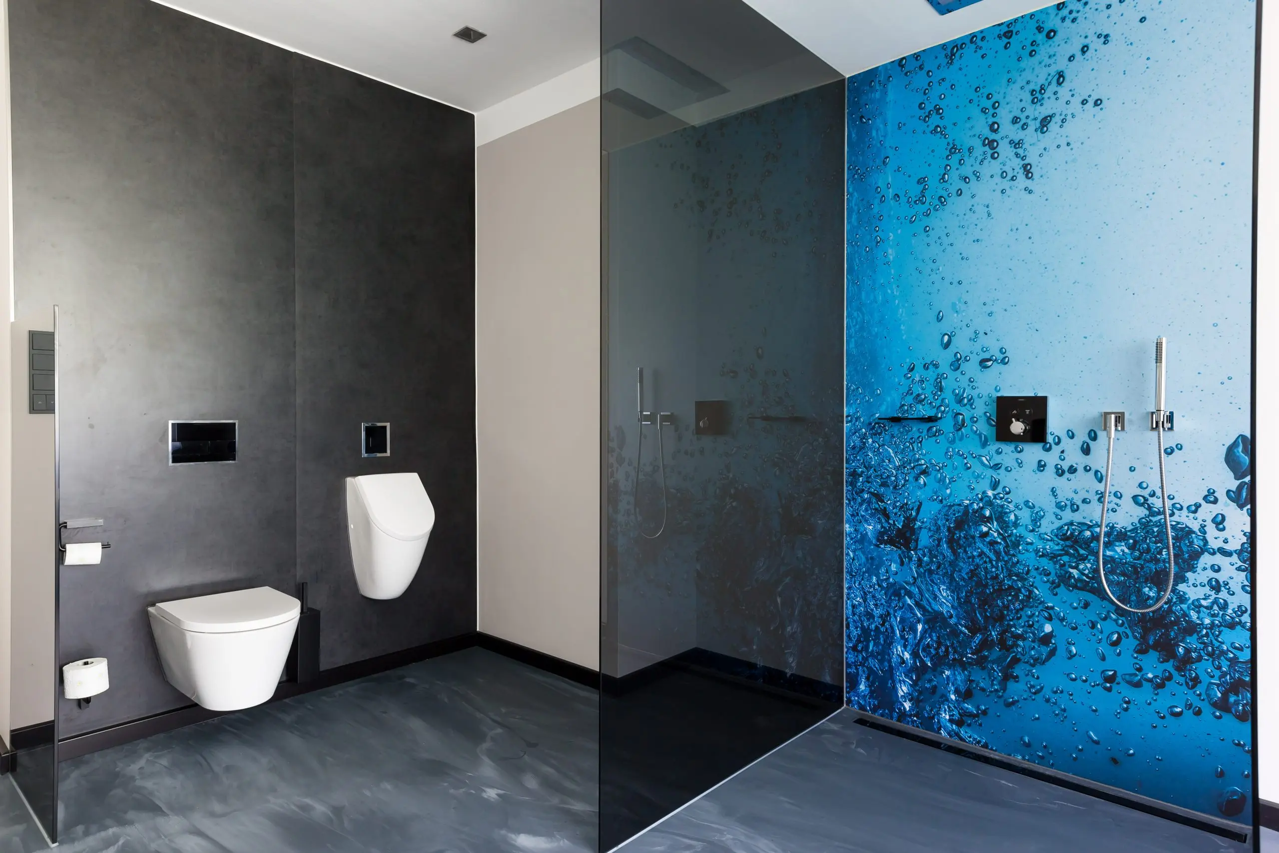 Sanitärbereich mit dunklem Steinboden und blau gemusterter Glaswand