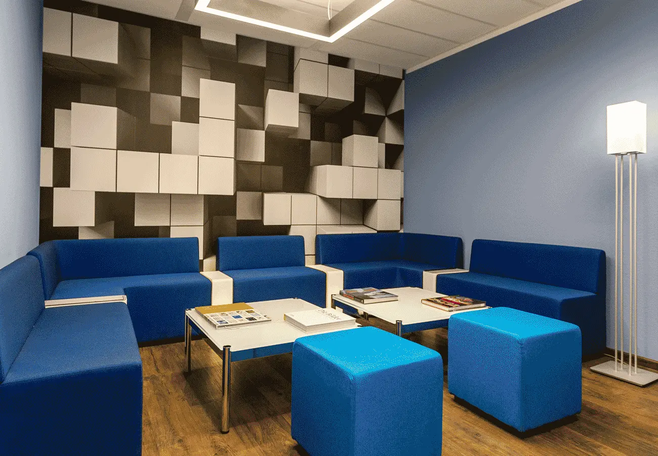 Rückzugsraum mit blauen Sofas vor einer Akustikwand aus schwarz-weißen Würfeln