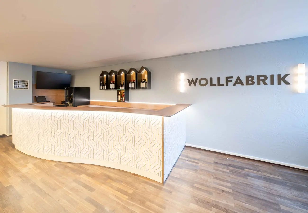 Geschwungene helle Theke des Ticketshops mit dem Schriftzug Wollfabrik